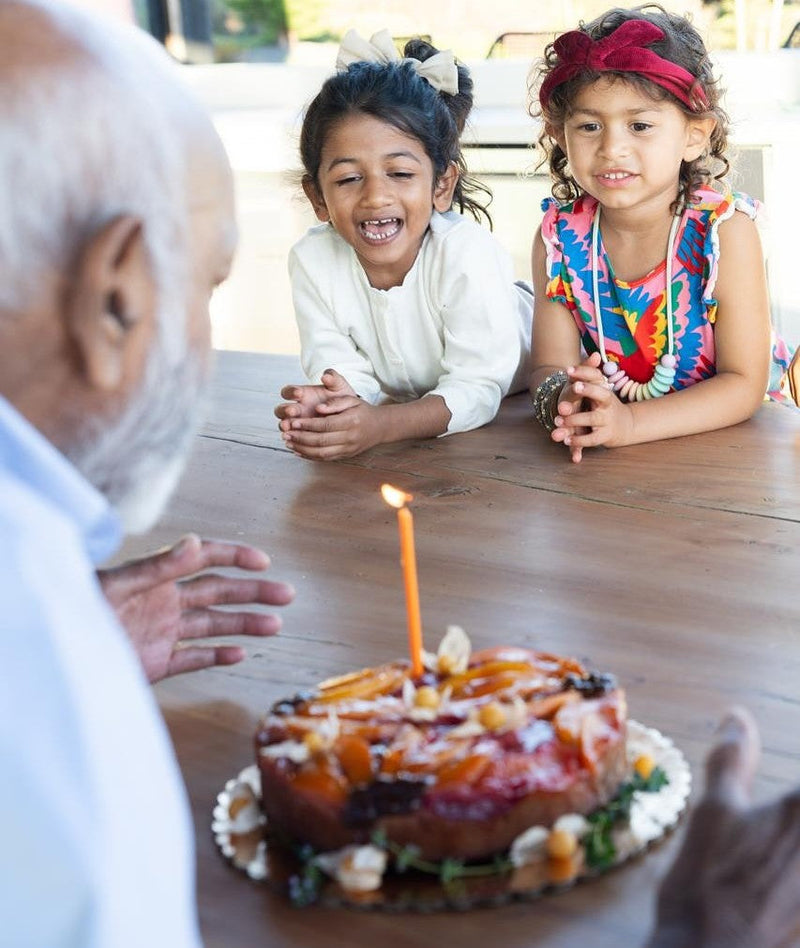 Grandfather and two young granddaughters celebrating a birthday with a date cake from Just Date.