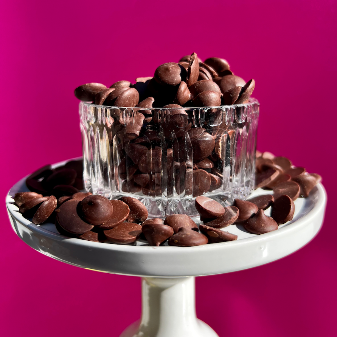 Organic dark chocolate chips in a glass bowl on a dessert stand