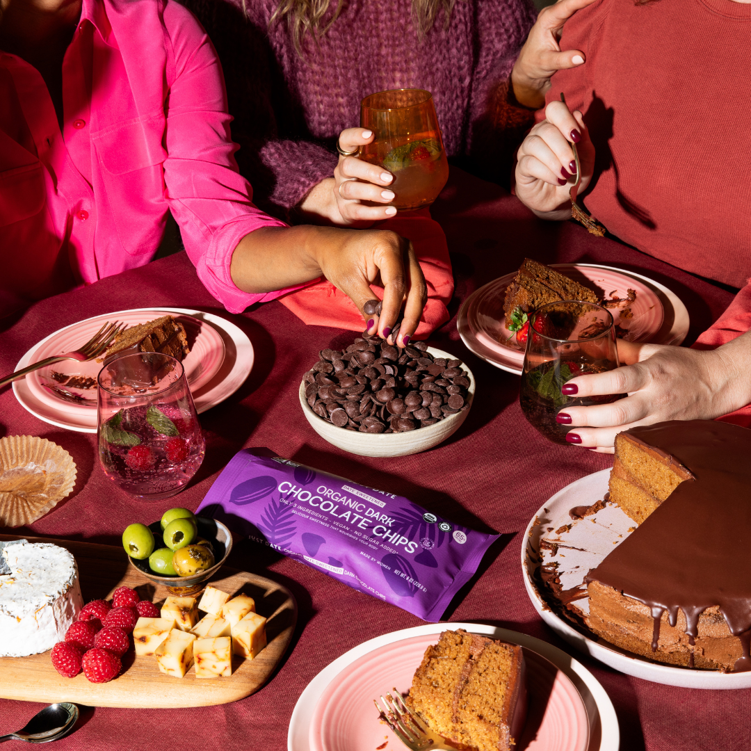 Organic dark chocolate chips displayed on a dessert table with cakes, berries, and drinks