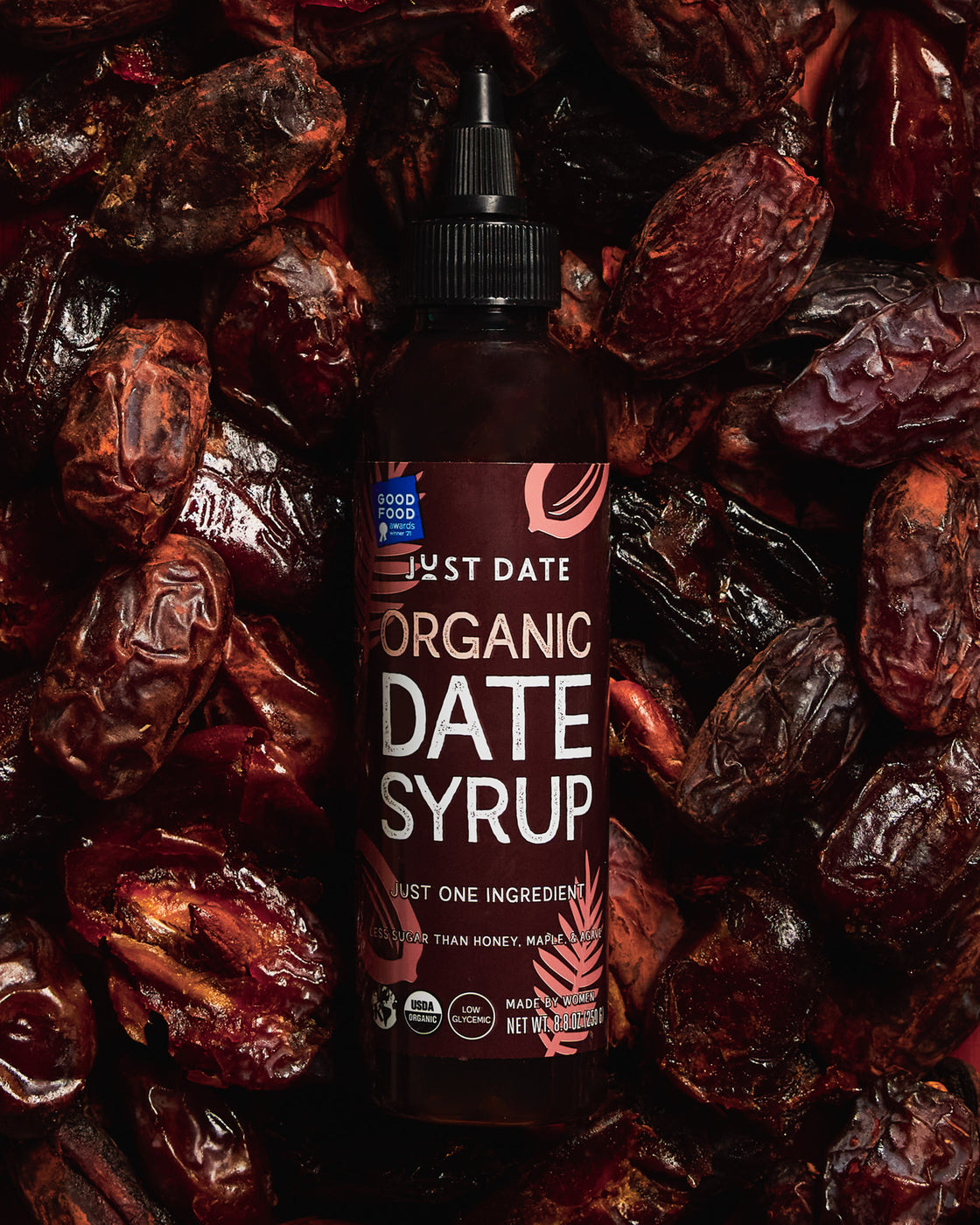 Bottle of Just Date Organic Date Syrup surrounded by dried dates