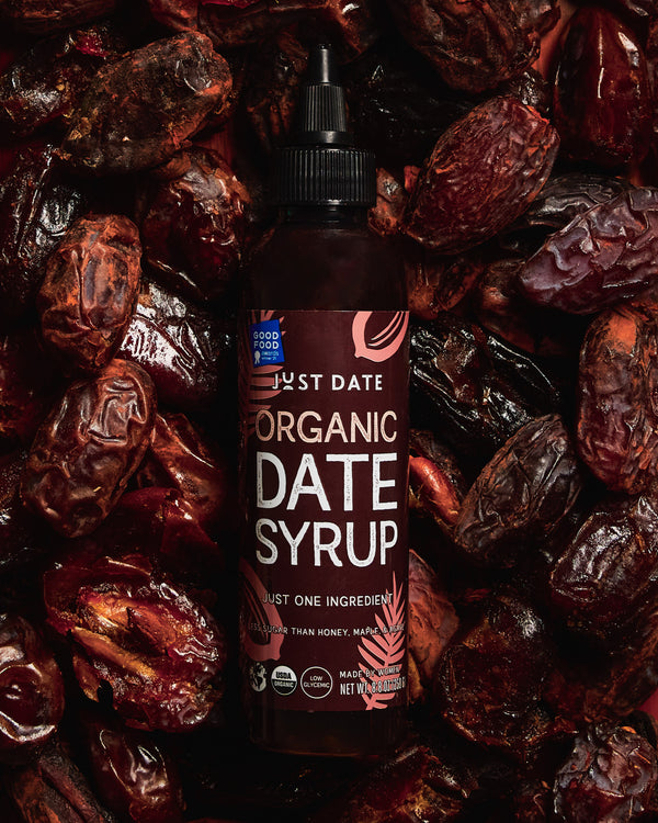 Bottle of Just Date Organic Date Syrup surrounded by dried dates
