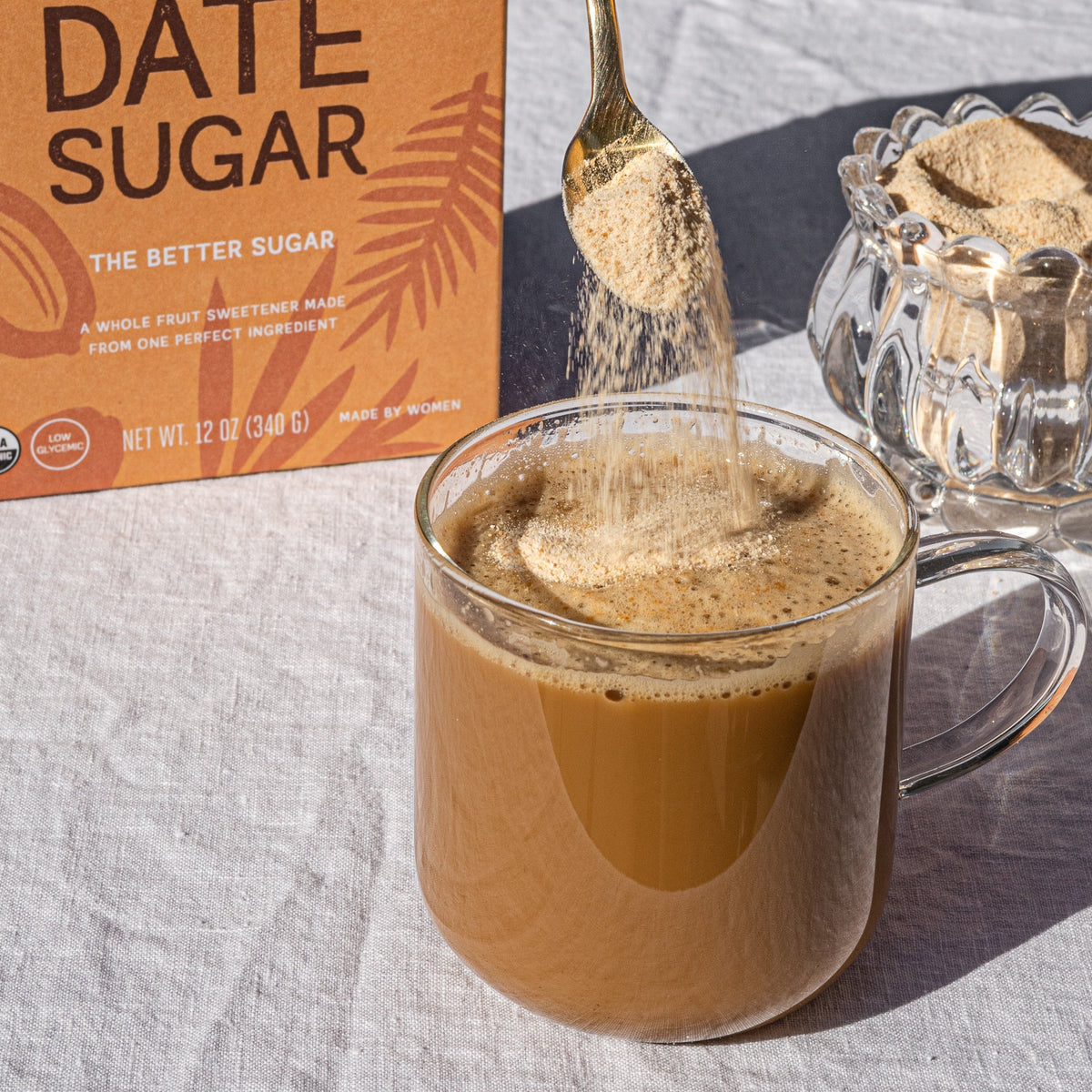 Organic date sugar being poured into a warm beverage from a spoon
